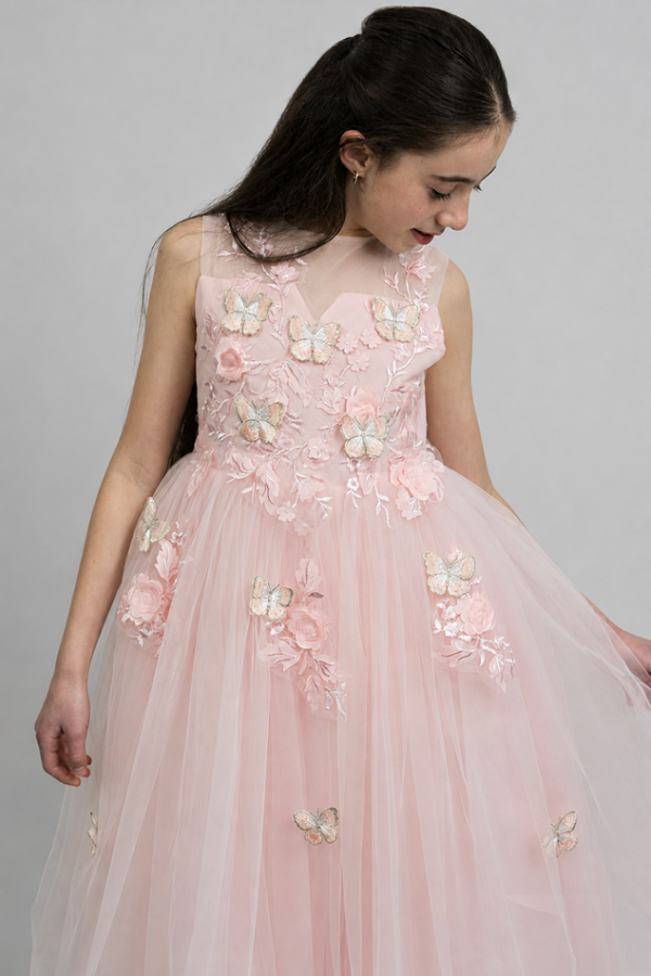 Girl wearing the KoKo Mariposa blush-pink tulle party dress with a sheer illusion neckline, 3D butterflies, floral appliqués and a full A-line skirt.