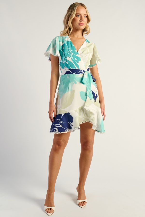 KoKo Fluer teal floral wrap dress with flutter sleeves, a side waist tie and a ruffled cream-trimmed hem, shown on a model